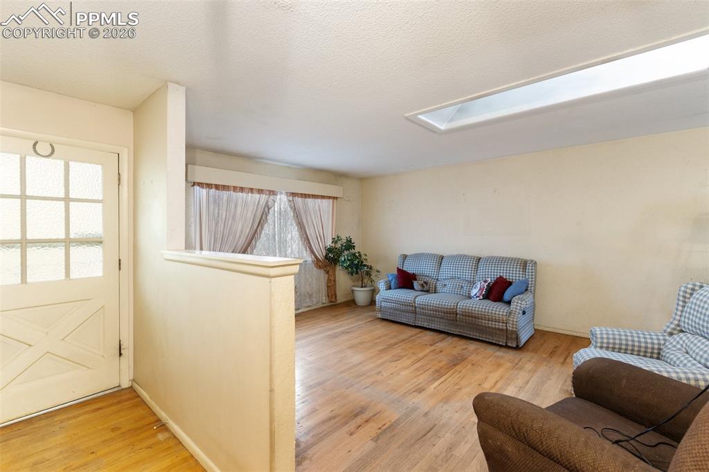 Image 5 of 34: Main level is bright with a skylight in the living room and wood flooring
