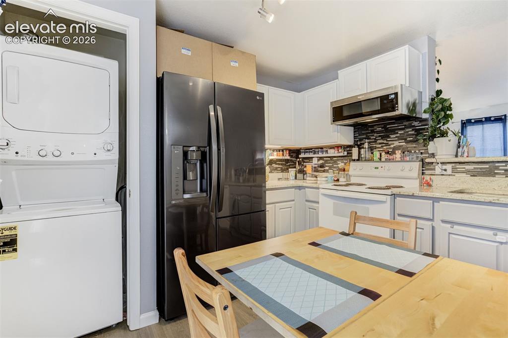 Image 10 of 43: White cabinetry with a tile backsplash, stainless steel over-the-range micr