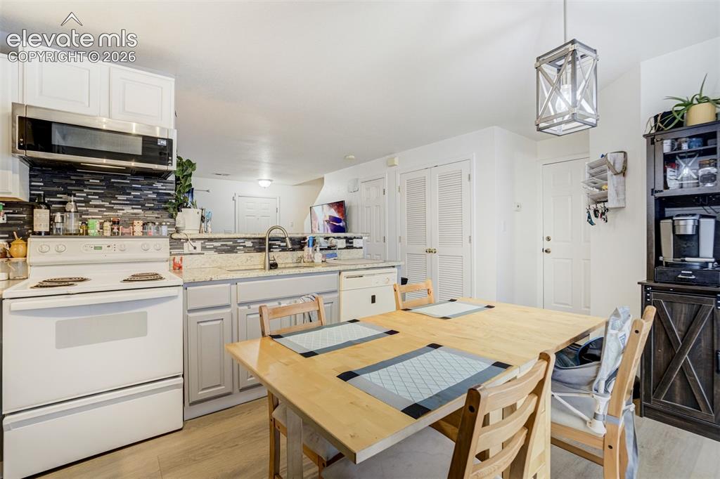 Image 12 of 43: Kitchen featuring white cabinetry, a mosaic tile backsplash, light-colored 