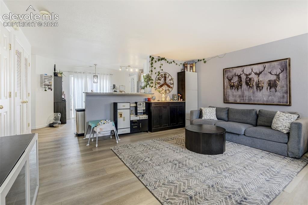 Image 16 of 43: Open-concept living space with wood-finish flooring, a partial wall, white