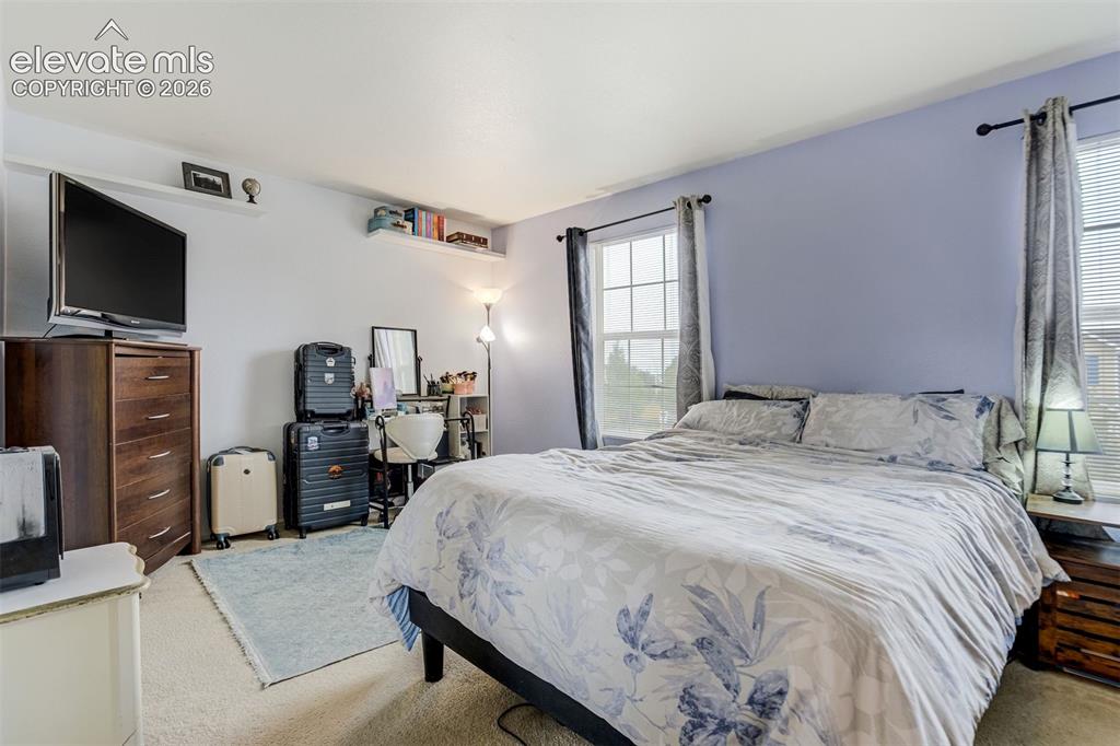 Image 18 of 43: Wall-mounted shelving, two windows with blinds and curtains, and neutral ca