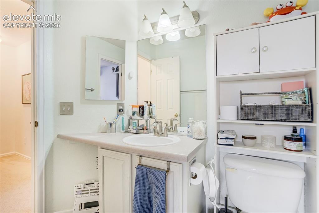 Image 23 of 43: White vanity with an integrated sink and brushed nickel faucet, illuminated