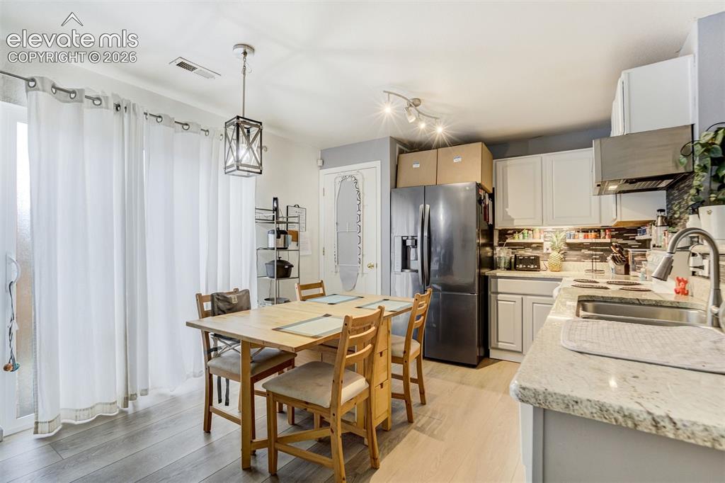Image 6 of 43: Wood-finish flooring, white cabinetry, light-toned countertops, and a tile 