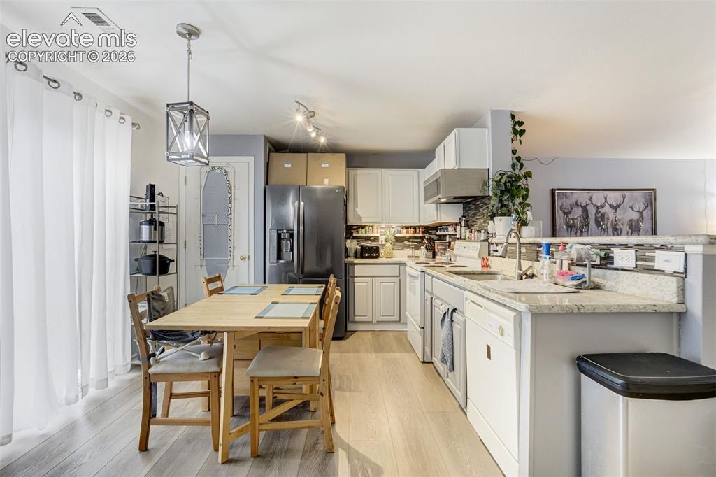 Image 7 of 43: Contemporary kitchen featuring light wood-finish flooring, white cabinetry,