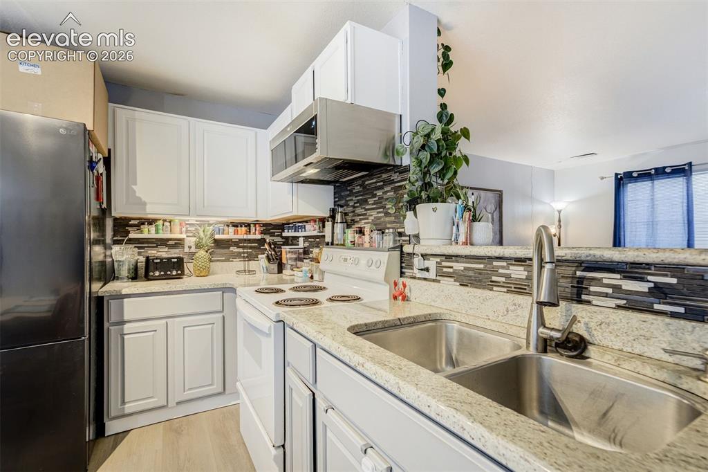 Image 8 of 43: Kitchen featuring white cabinetry, stone-finish countertops, stainless stee