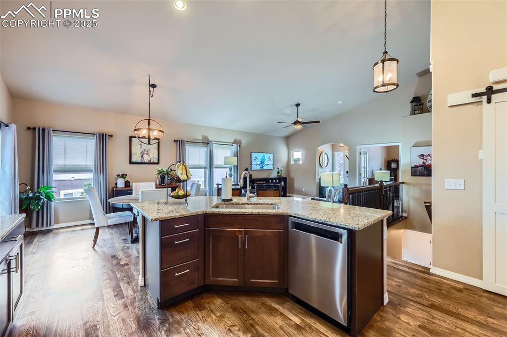 Image 10 of 47: Kitchen featuring a barn door, dishwasher, dark wood-style floors, dark bro