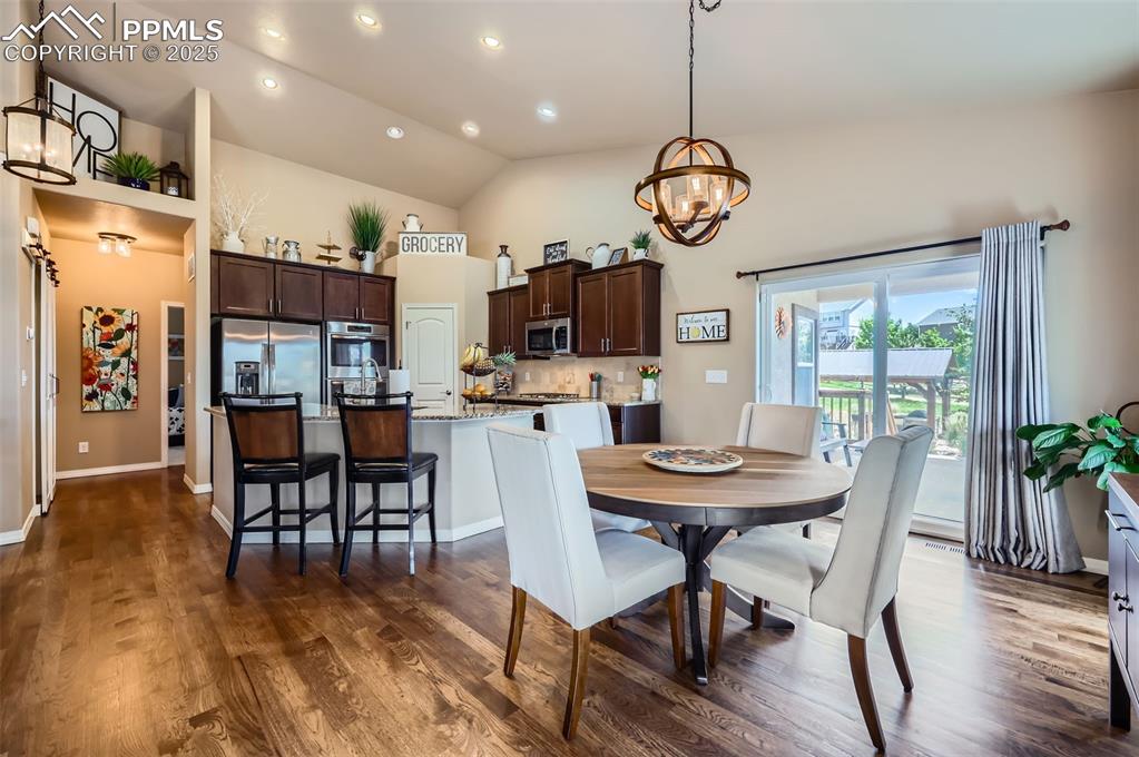 Image 11 of 47: Dining space featuring a chandelier, high vaulted ceiling, dark wood finish