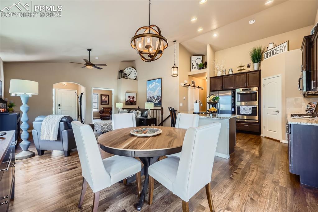 Image 12 of 47: Dining room with arched walkways, ceiling fan, high vaulted ceiling, dark w