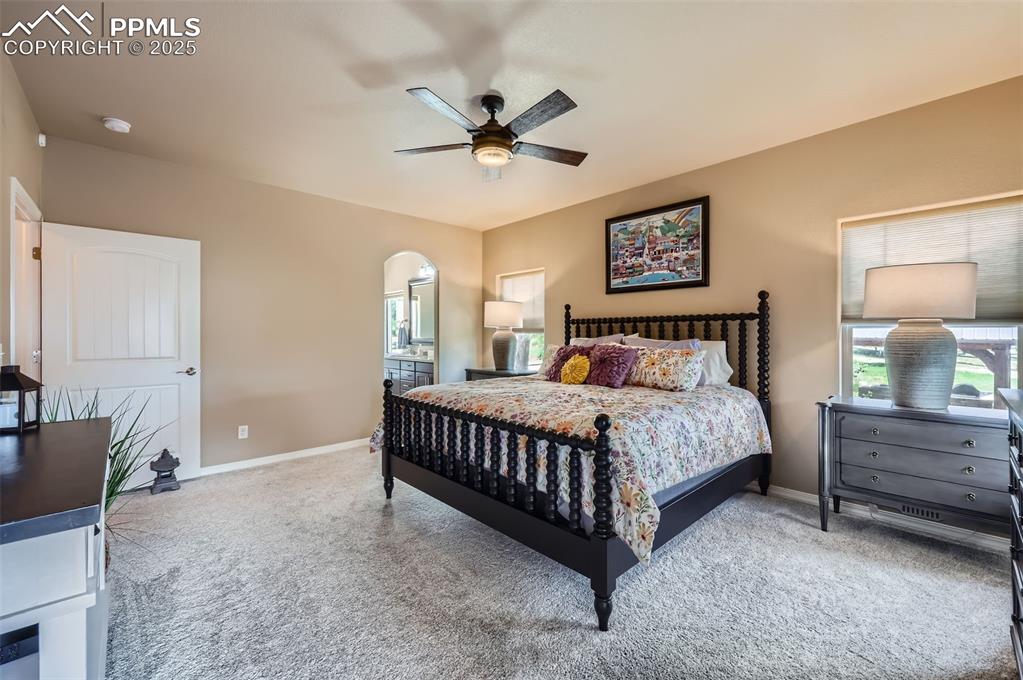 Image 13 of 47: Carpeted bedroom featuring arched walkways and a ceiling fan