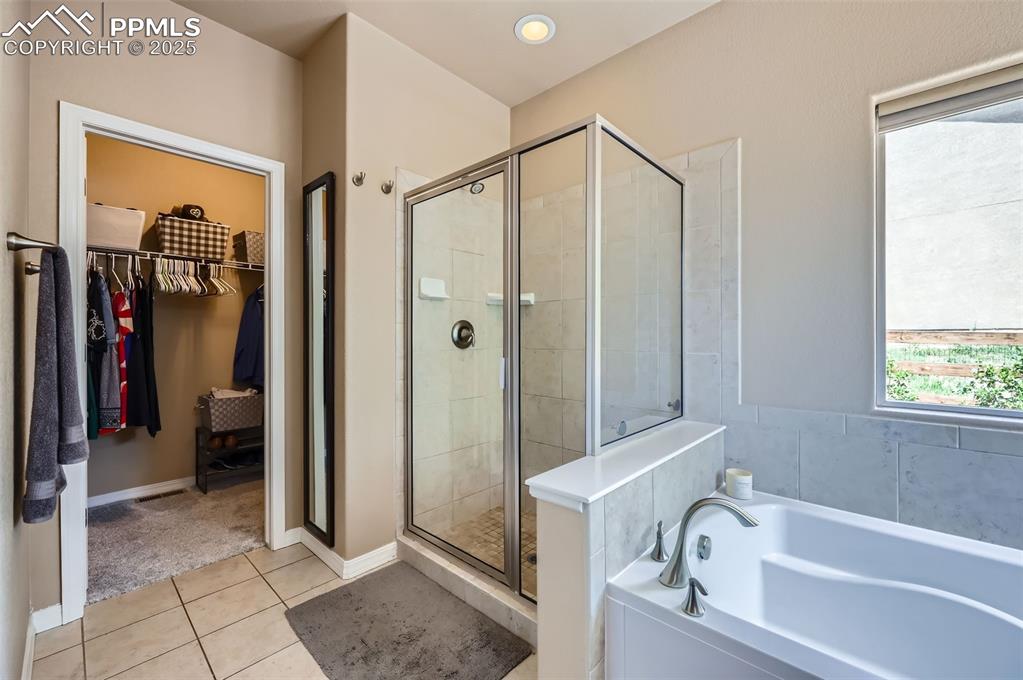 Image 16 of 47: Bathroom with a garden tub, a walk in closet, a shower stall, and tile patt