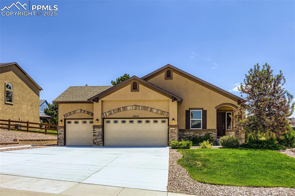 Image 2 of 47: View of front of house with stone siding, an attached garage, stucco siding