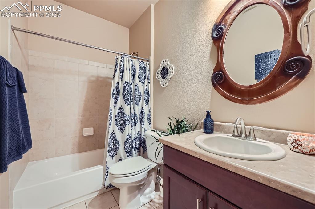 Image 20 of 47: Bathroom with vanity, tile patterned floors, shower / tub combo with curtai