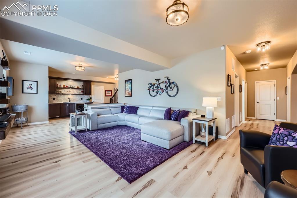 Image 22 of 47: Living area featuring bar with sink and light wood-style floors