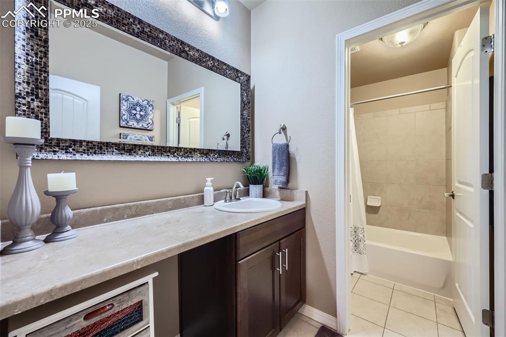 Image 27 of 47: Bathroom with tile patterned floors, vanity, and shower / bath combo with s