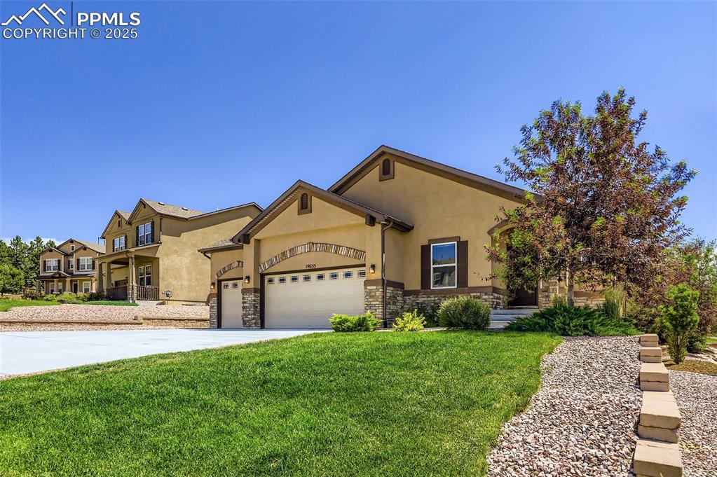 Image 3 of 47: View of front of home featuring stucco siding, a garage, a front lawn, ston