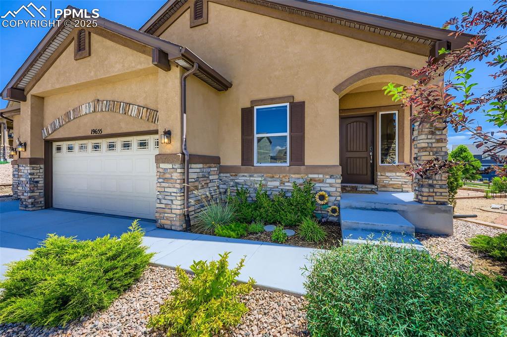 Image 4 of 47: View of front of house featuring stone siding, an attached garage, driveway