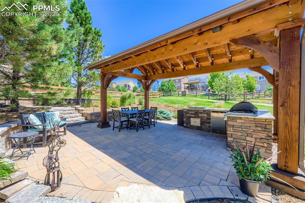 Image 43 of 47: Fenced backyard featuring an outdoor kitchen, a gazebo, outdoor dining spac