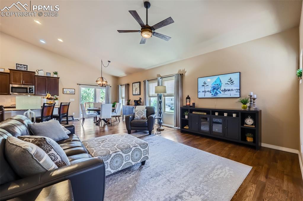 Image 5 of 47: Living room with dark wood-style floors, ceiling fan, lofted ceiling, reces
