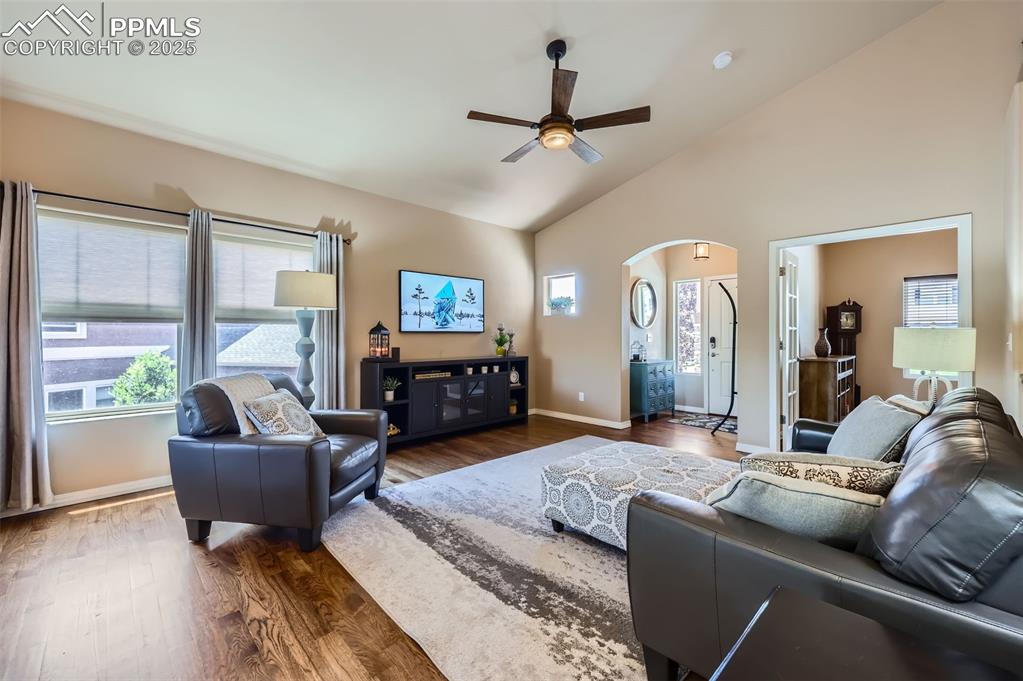 Image 7 of 47: Living room featuring a ceiling fan, dark wood-type flooring, arched walkwa