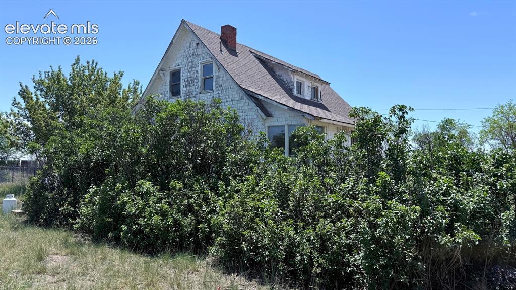 Image 3 of 9: White clapboard siding exterior with a dark shingle roof and a red brick ch