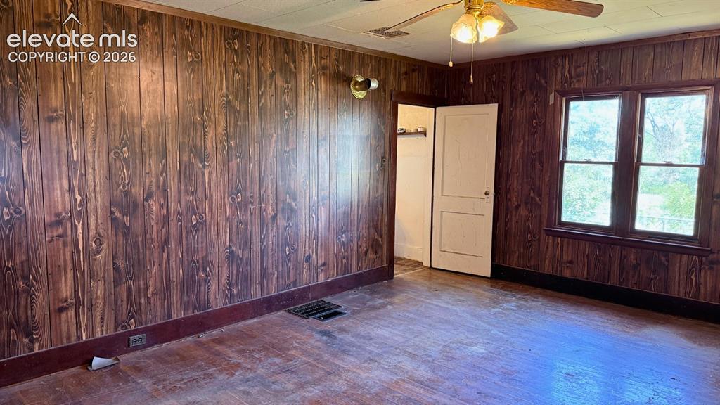 Image 5 of 9: Interior room featuring wood-panel walls, wood-finish flooring, a ceiling f