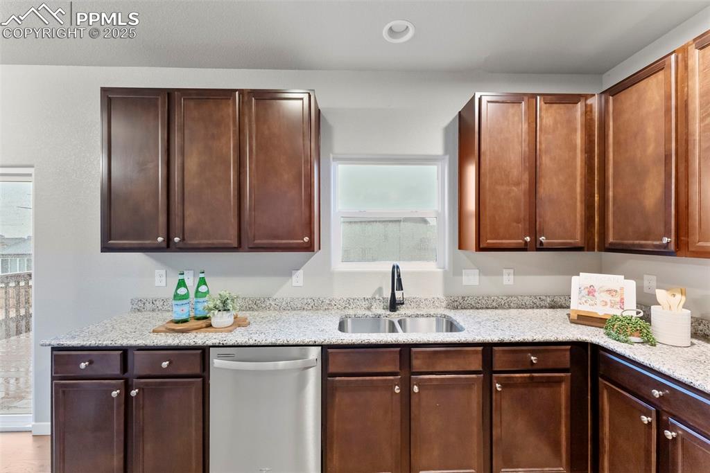 Image 11 of 50: Kitchen featuring stainless steel dishwasher, light stone counters, and rec