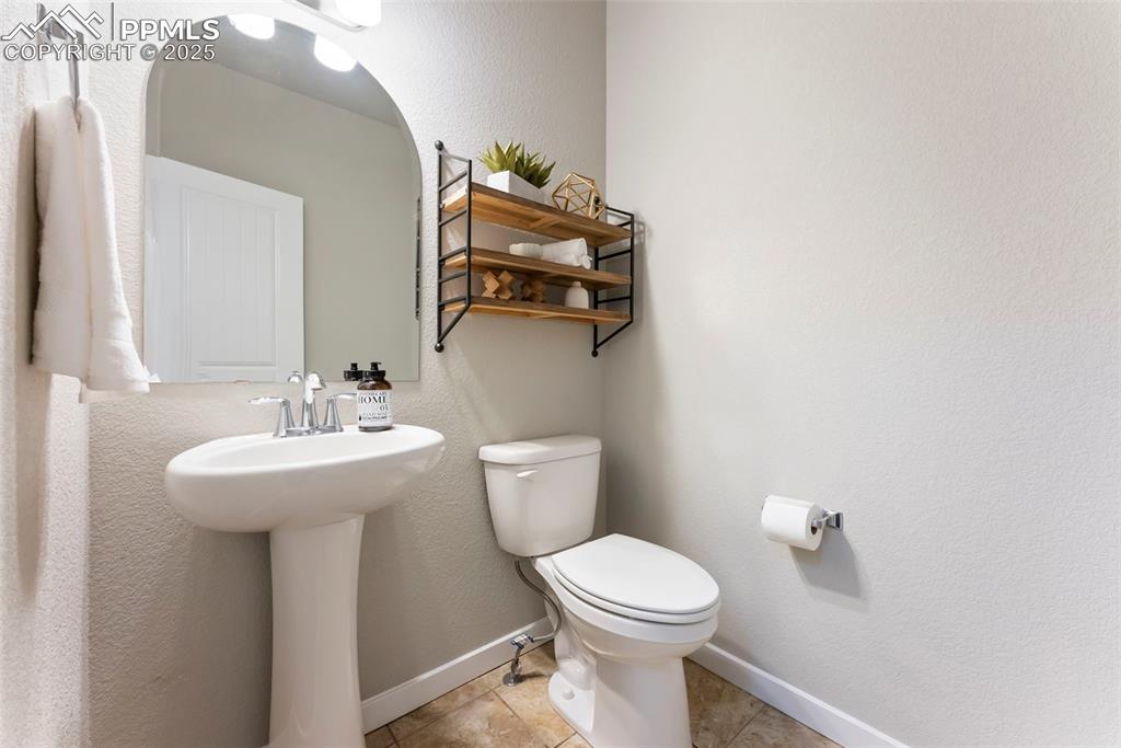 Image 13 of 50: Half bathroom featuring a textured wall and light tile patterned flooring