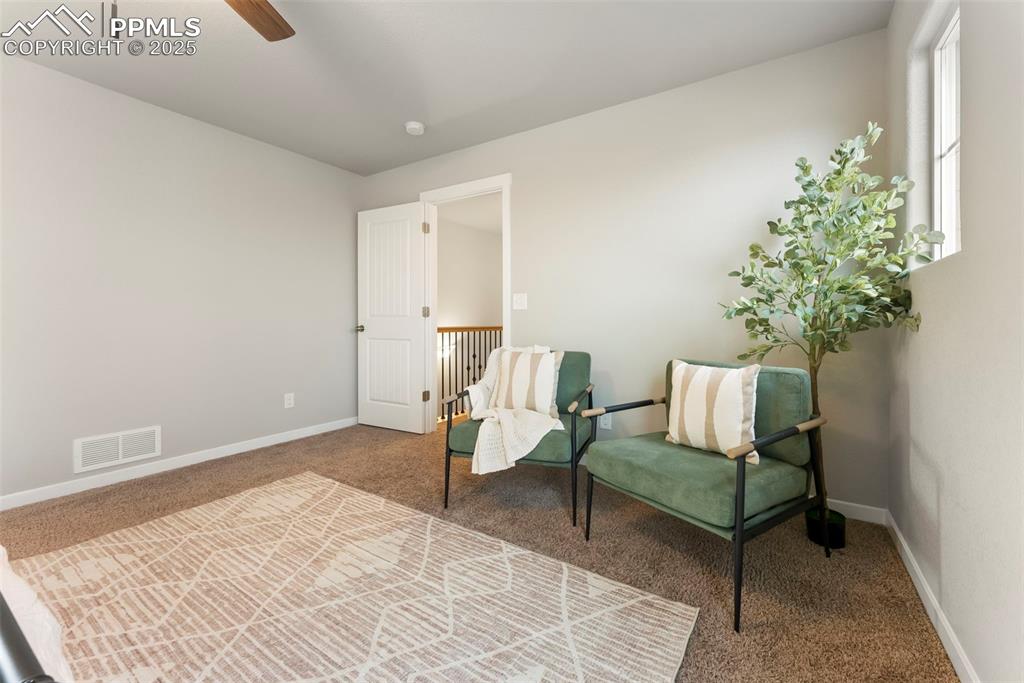 Image 19 of 50: Living area with carpet floors and ceiling fan