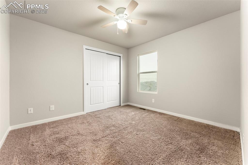 Image 24 of 50: Unfurnished bedroom with carpet flooring, a closet, and ceiling fan