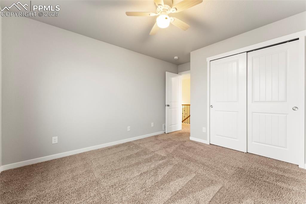 Image 28 of 50: Unfurnished bedroom with carpet floors, a closet, and ceiling fan