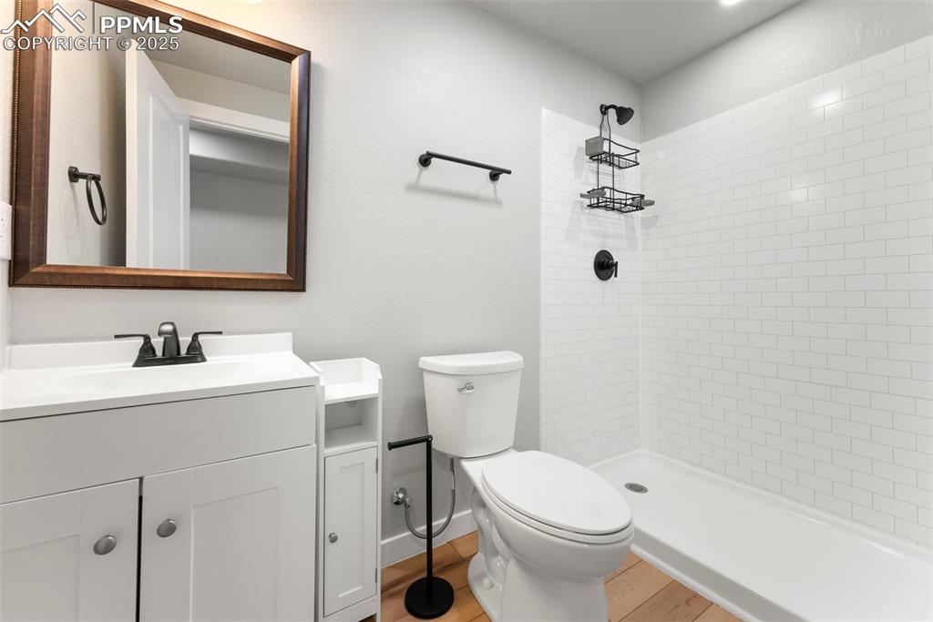 Image 38 of 50: Bathroom with vanity, tiled shower, and light wood-style floors