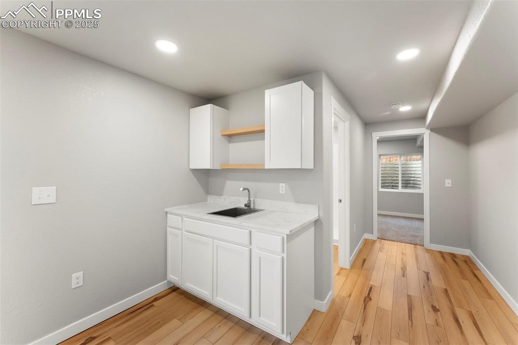 Image 39 of 50: Kitchen with white cabinetry, open shelves, light wood-type flooring, and r