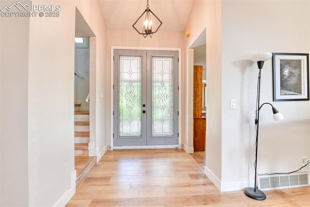 Image 10 of 50: Entrance foyer with french doors, stairs, baseboards, and light wood-style
