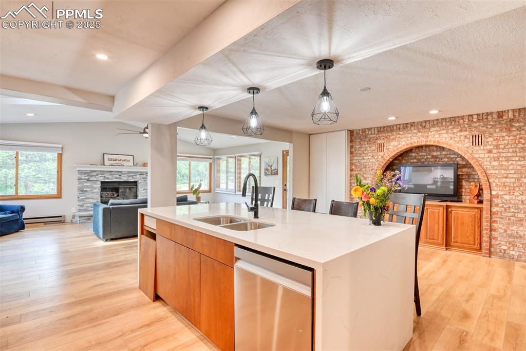Image 13 of 50: Kitchen with a sink, a stone fireplace, open floor plan, a center island wi