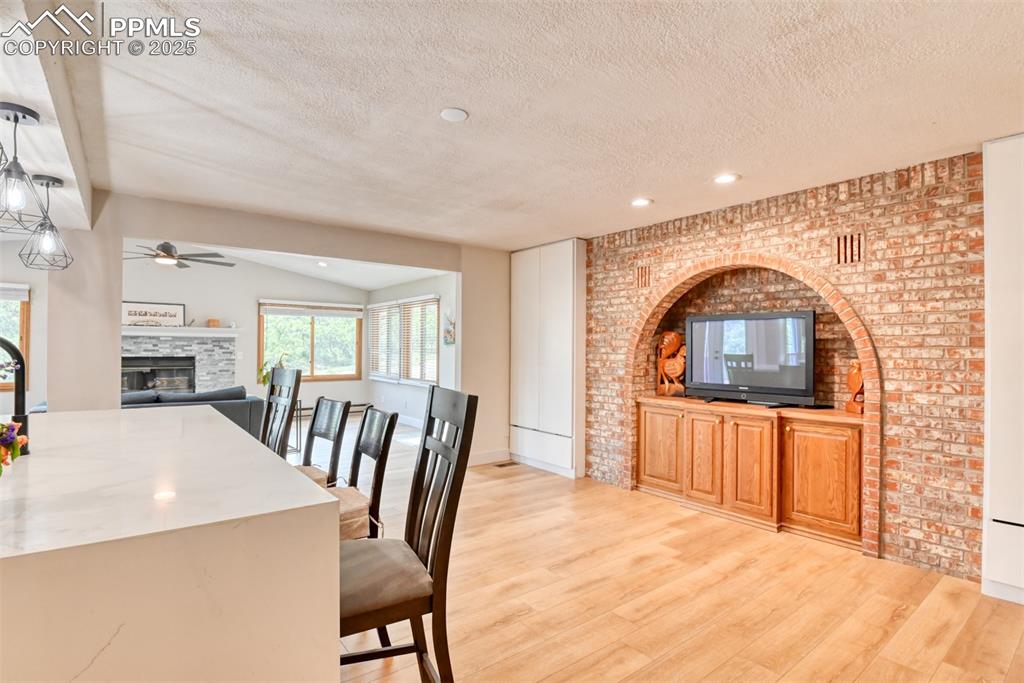Image 15 of 50: Dining space with a glass covered fireplace, a textured ceiling, a ceiling