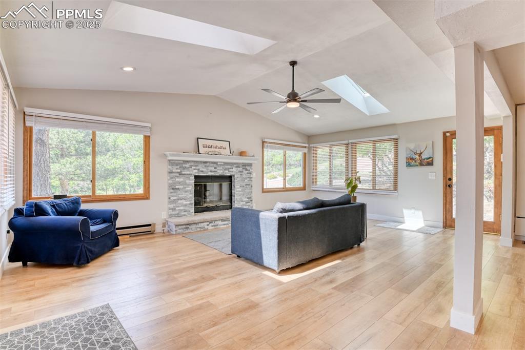 Image 16 of 50: Living area featuring a skylight, a baseboard heating unit, light wood-styl