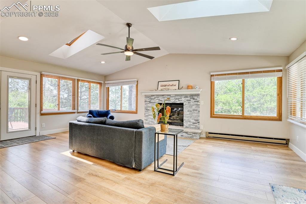 Image 17 of 50: Living room featuring a skylight, baseboard heating, light wood-type floori