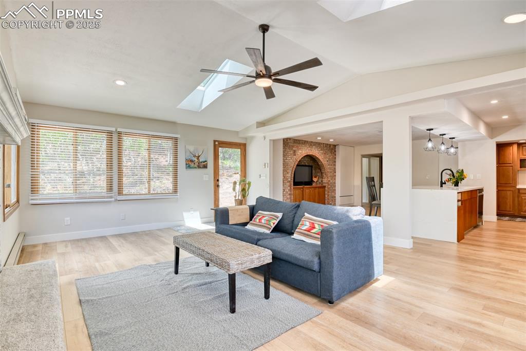 Image 18 of 50: Living area featuring a skylight, ceiling fan, light wood finished floors,