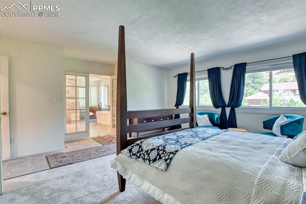 Image 20 of 50: Carpeted bedroom with a textured ceiling and connected bathroom