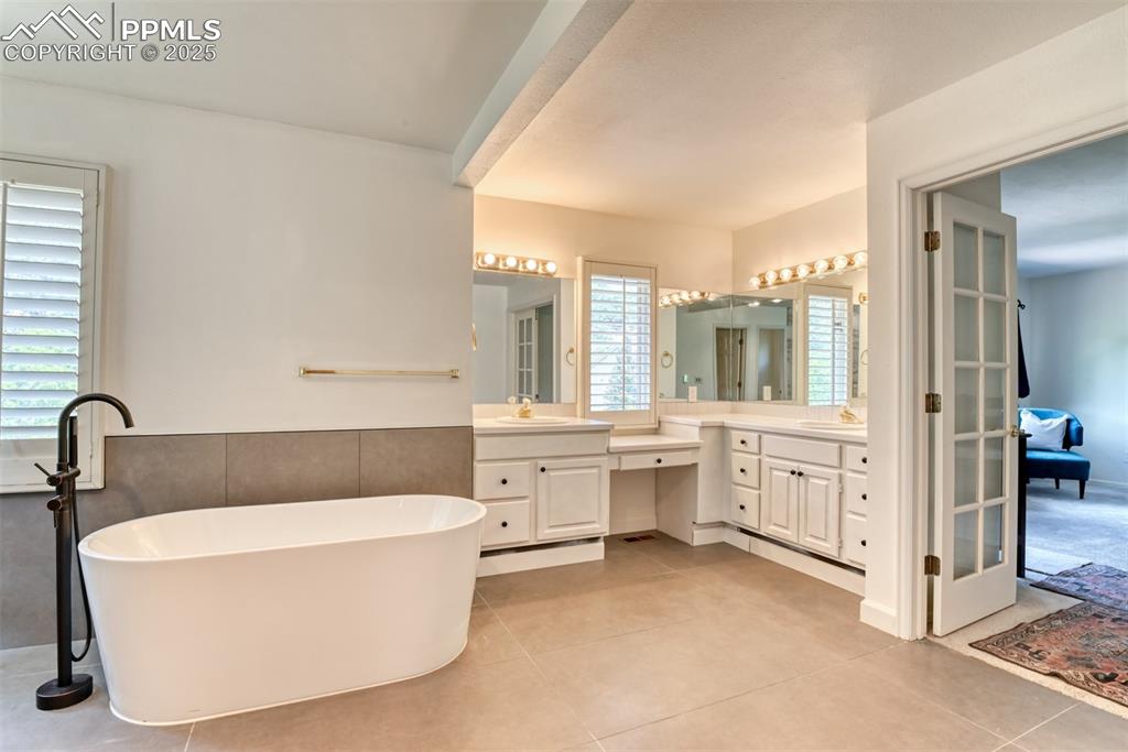 Image 25 of 50: Full bathroom featuring vanity, a soaking tub, and tile patterned floors