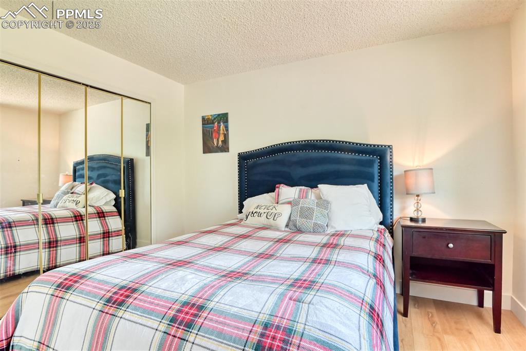 Image 26 of 50: Bedroom with wood finished floors, a textured ceiling, and a closet