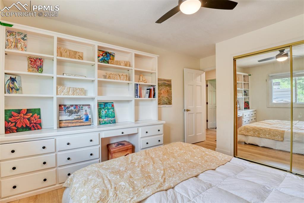 Image 29 of 50: Bedroom with light wood-style flooring, a closet, ceiling fan, and a desk