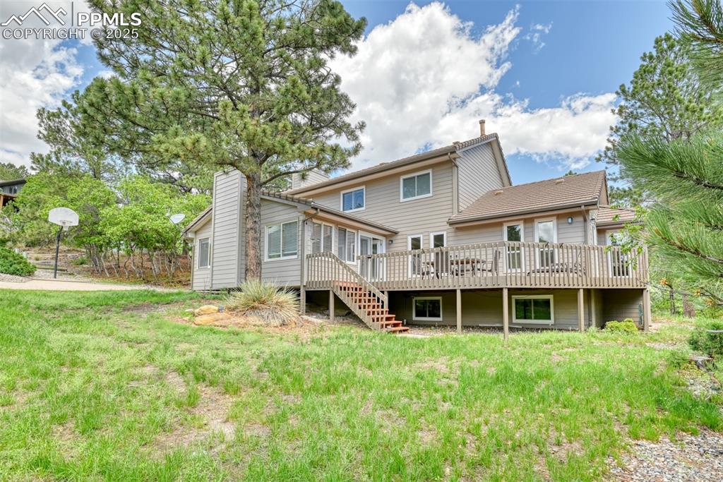 Image 3 of 50: Rear view of house featuring a wooden deck, a sunroom, a chimney, and stair