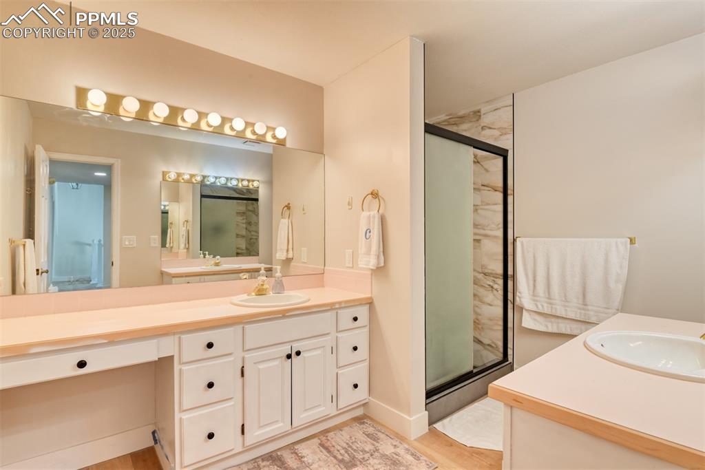 Image 33 of 50: Full bathroom featuring a stall shower, vanity, and wood finished floors