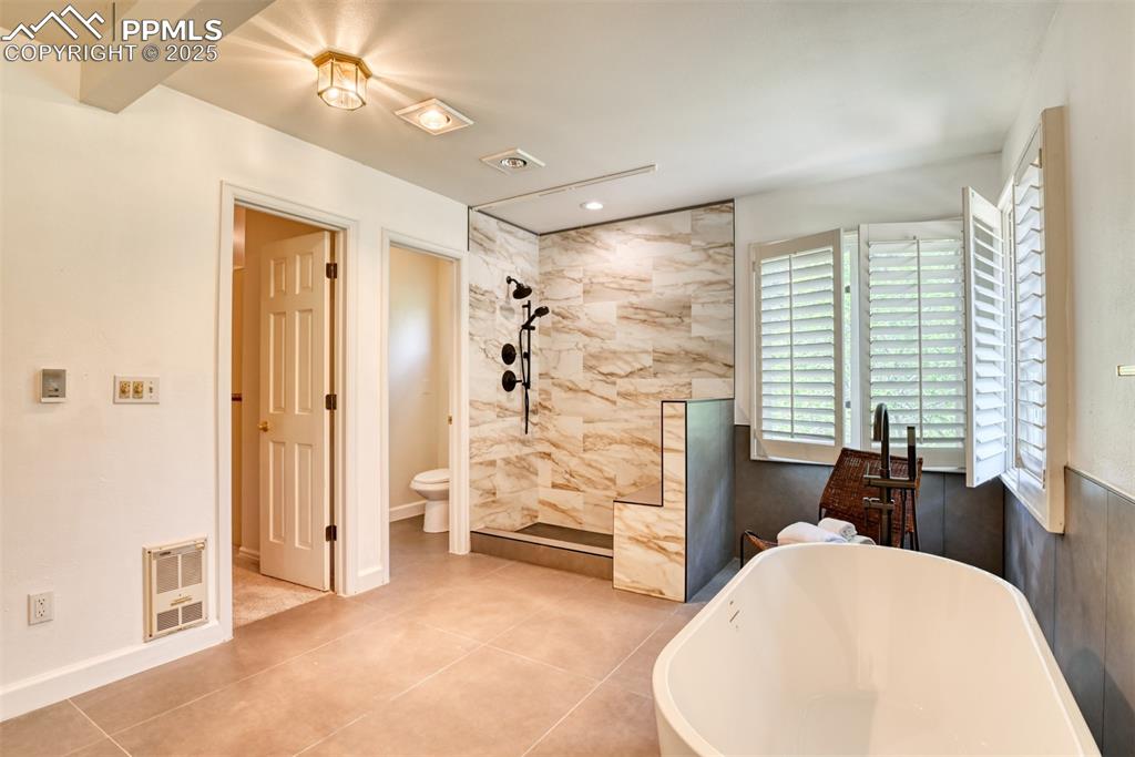 Image 34 of 50: Bathroom with heating unit, a freestanding tub, tiled shower, toilet, and t