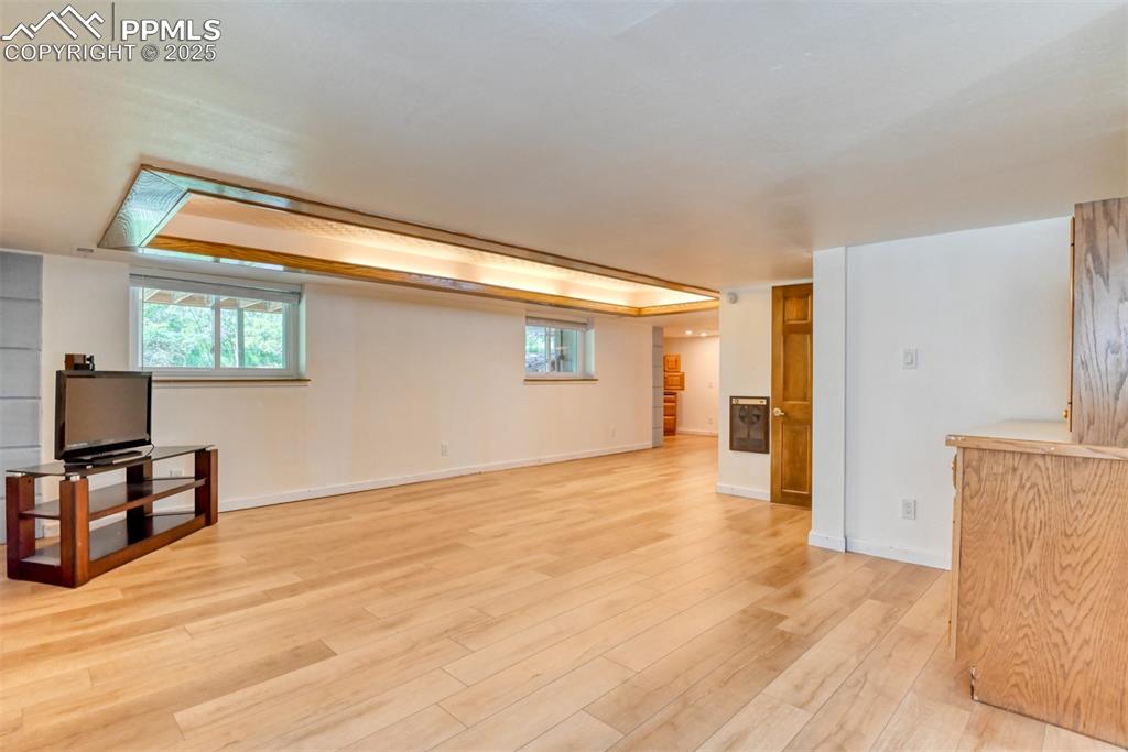 Image 35 of 50: Basement living room with light wood finished floors and baseboards