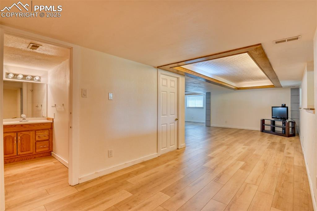 Image 37 of 50: Basement living room with light wood-type flooring and baseboards