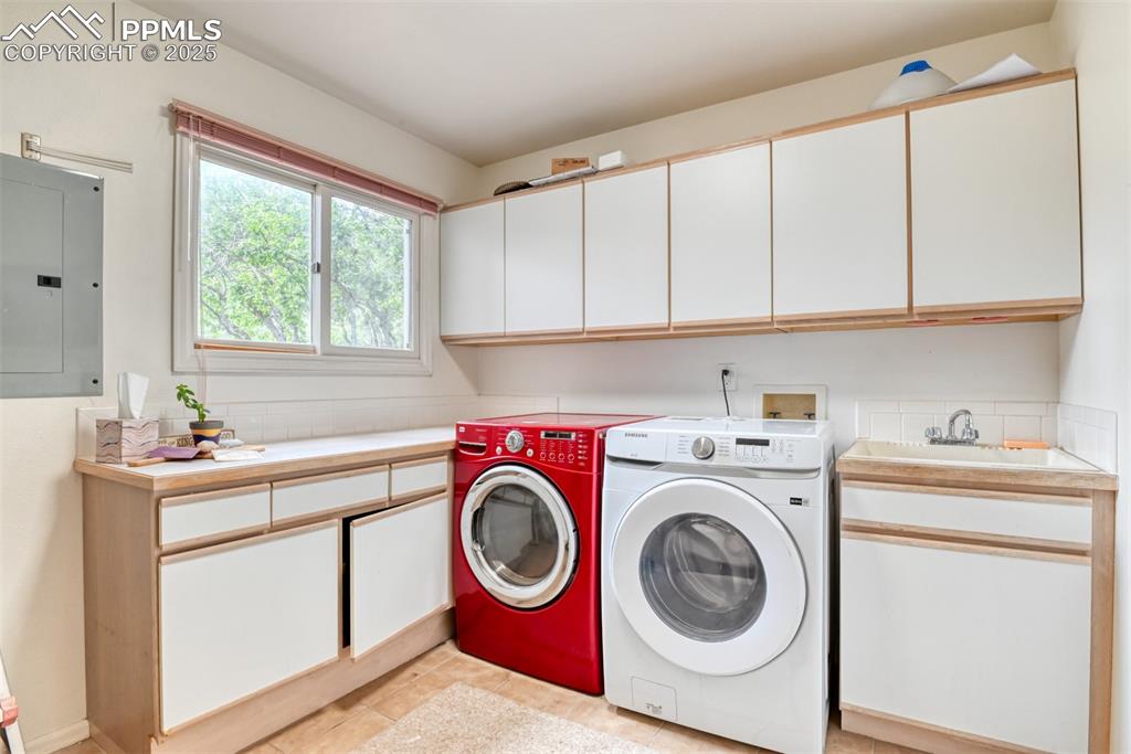 Image 43 of 50: Laundry area featuring electric panel, washing machine and dryer, cabinet s