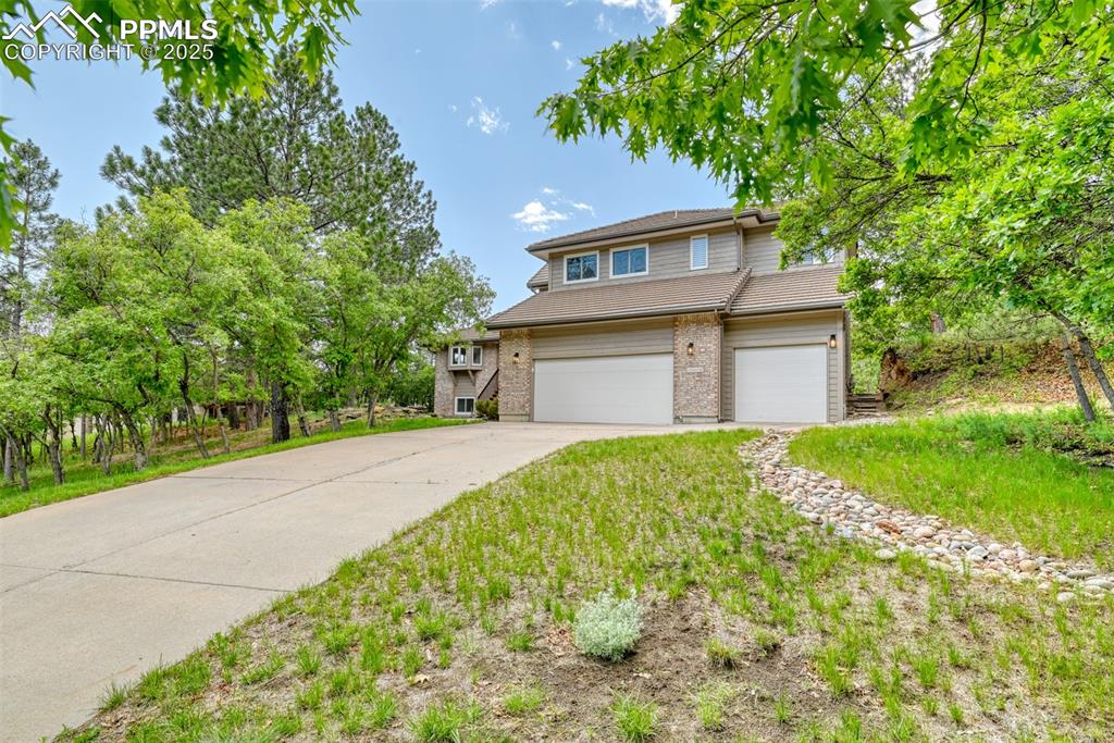 Image 44 of 50: Traditional-style home with driveway, an attached garage, and brick siding