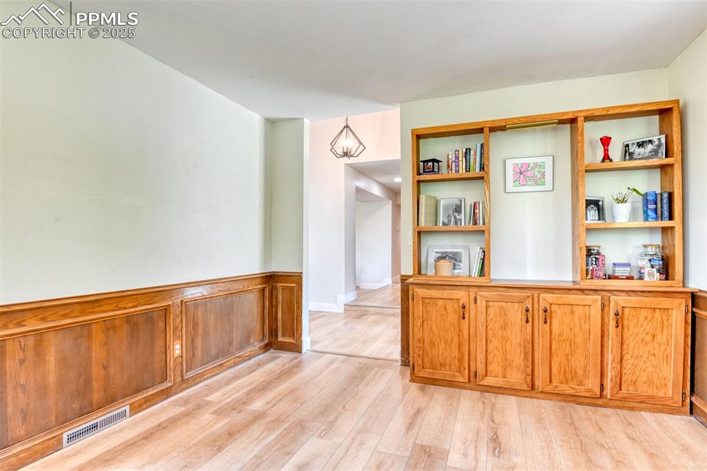 Image 5 of 50: Front room with light wood-type flooring and wainscoting
